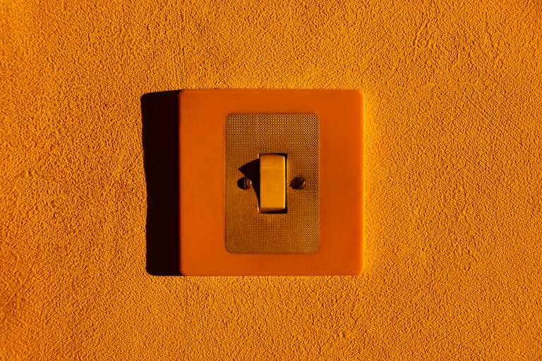 Close-up of a yellow light switch on a textured wall, highlighting minimalism.