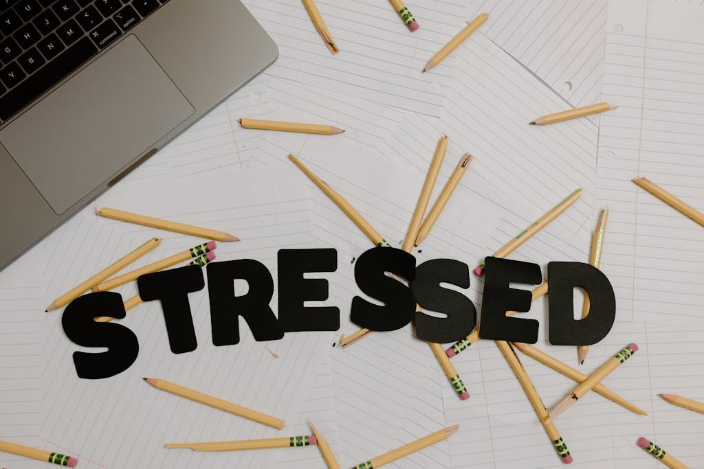 Overhead view of a stressed workplace setup with broken pencils scattered around a laptop.