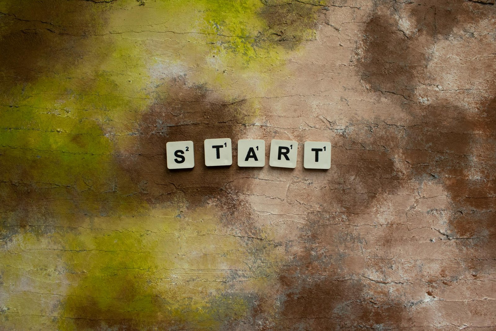 Scrabble letters spelling "START" on a textured earthy background.