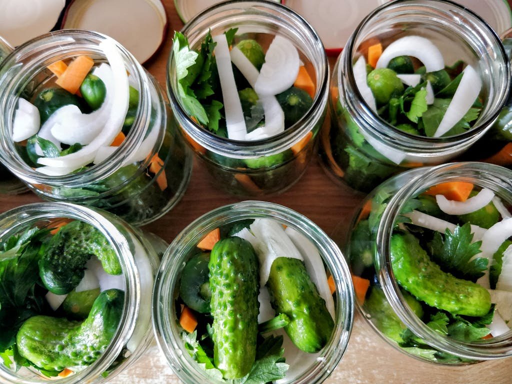 Top view of jars filled with fresh cucumbers, onions, and parsley, ready for pickling.