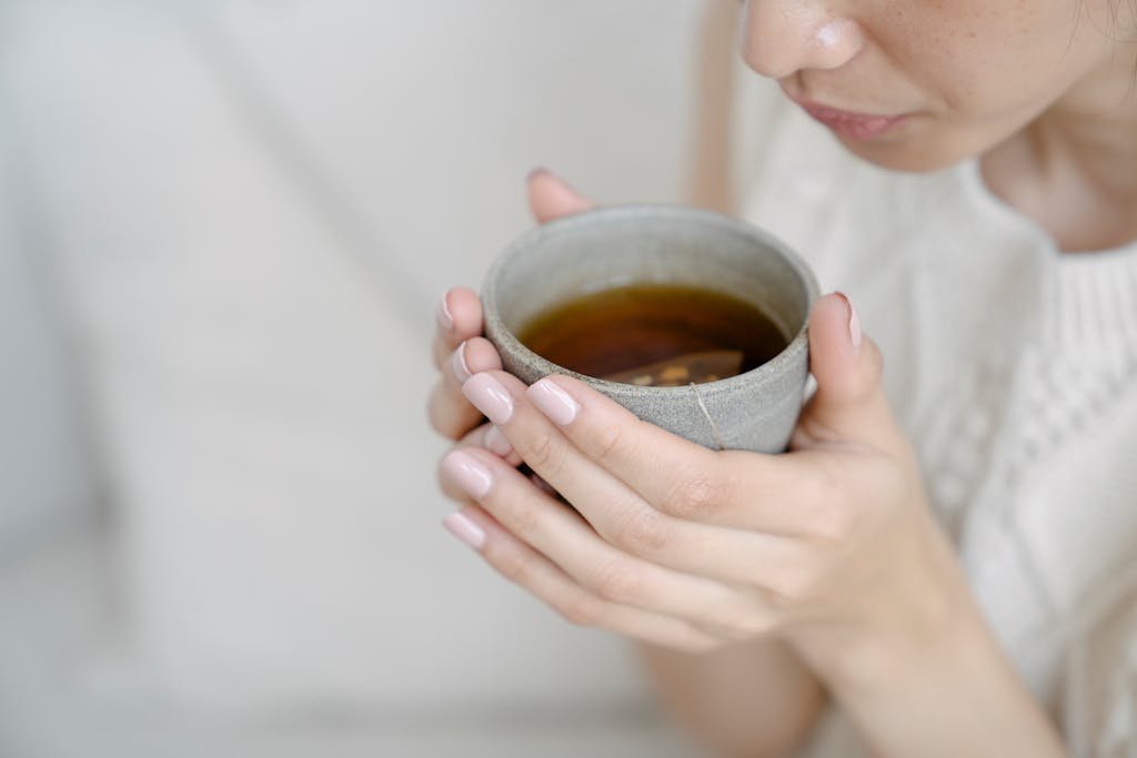 Close-up of a woman holding a hot cup of tea, illustrating warmth and relaxation.