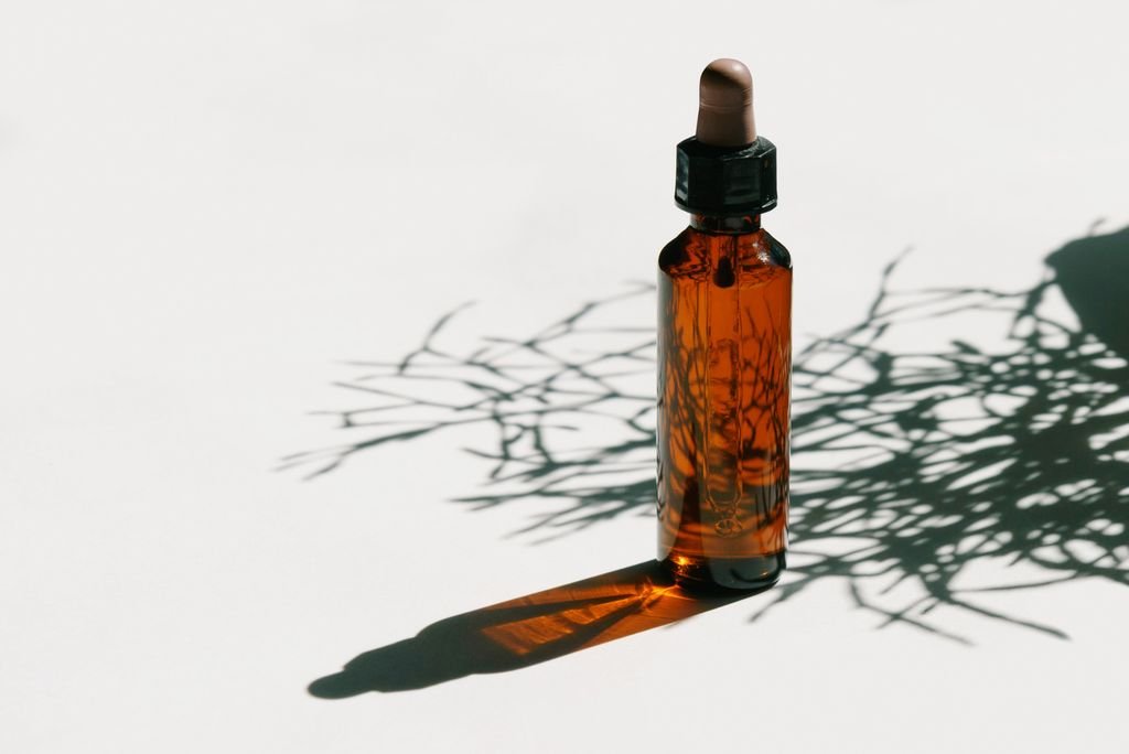 Brown glass dropper bottle casting shadows in a minimalist setting, ideal for beauty or health products.