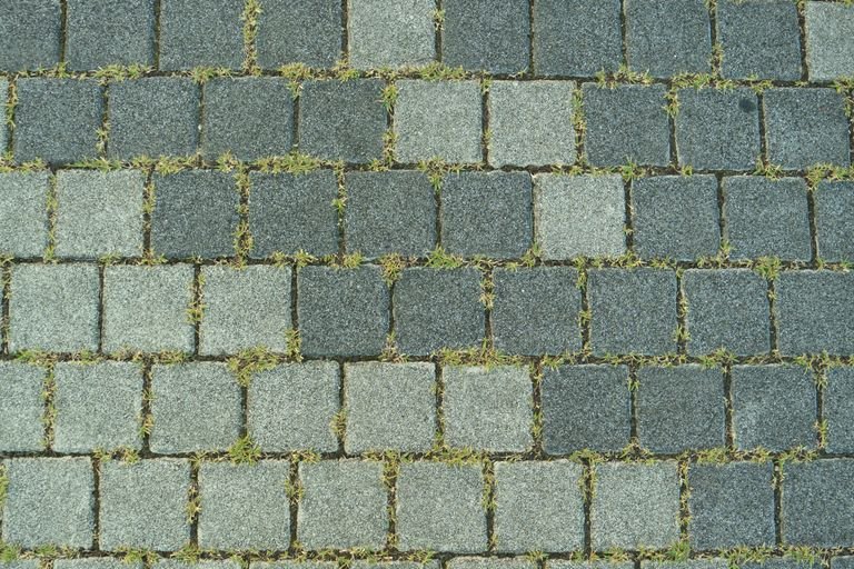Close-up of a stone paved sidewalk with grass growing between the stones in Toyohashi, Japan.